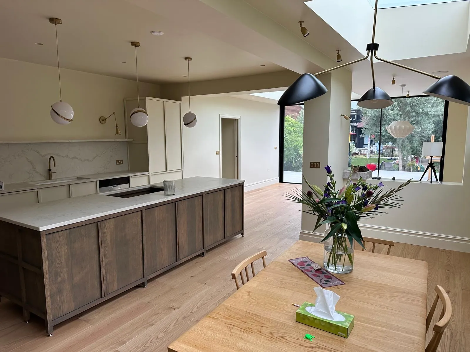 Completed kitchen extension with island, brass pendant lighting and garden view
