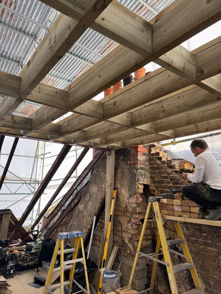 Bricklayer building up the gable wall in matching brick beneath the new loft floor structure