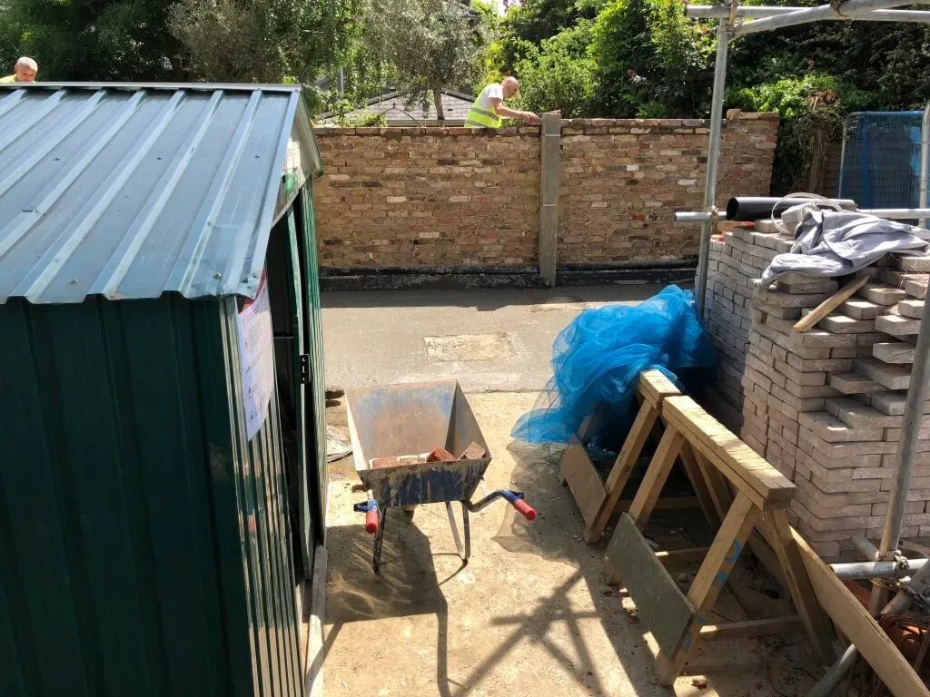 New brick garden wall under construction along the boundary of the Wandsworth new-build